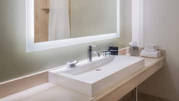 A modern bathroom with a large mirror, a sink, and a towel rack.