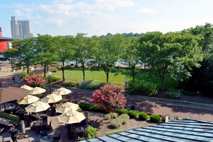 An outdoor patio area with tables and chairs, surrounded by trees and a view of a body of water.