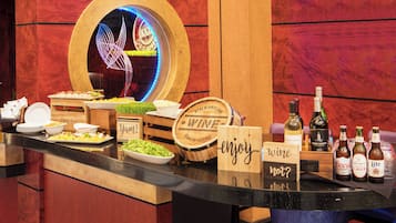 Montaje de buffet con diversos alimentos, un barril de vino y varias botellas de cerveza.