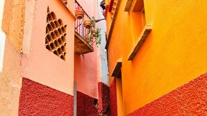 Une ruelle étroite avec un escalier menant à un immeuble à la façade rose et jaune.