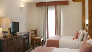 Habitación de hotel con dos camas, un televisor en una cómoda, una silla y un ventilador de techo.