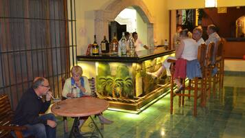 Zona de bar con mostrador, asientos y un fondo decorativo.