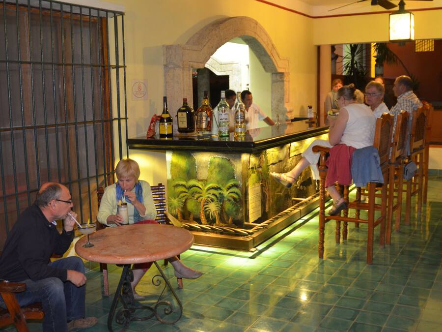 Zona de bar con mostrador, asientos y un fondo decorativo.