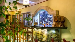 Un espace bar avec des chaises en bois, un comptoir et des éléments décoratifs, comme une fresque murale et un tonneau en bois.
