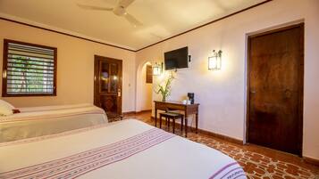 A hotel room with two beds, a desk, a chair, a television, and a door.