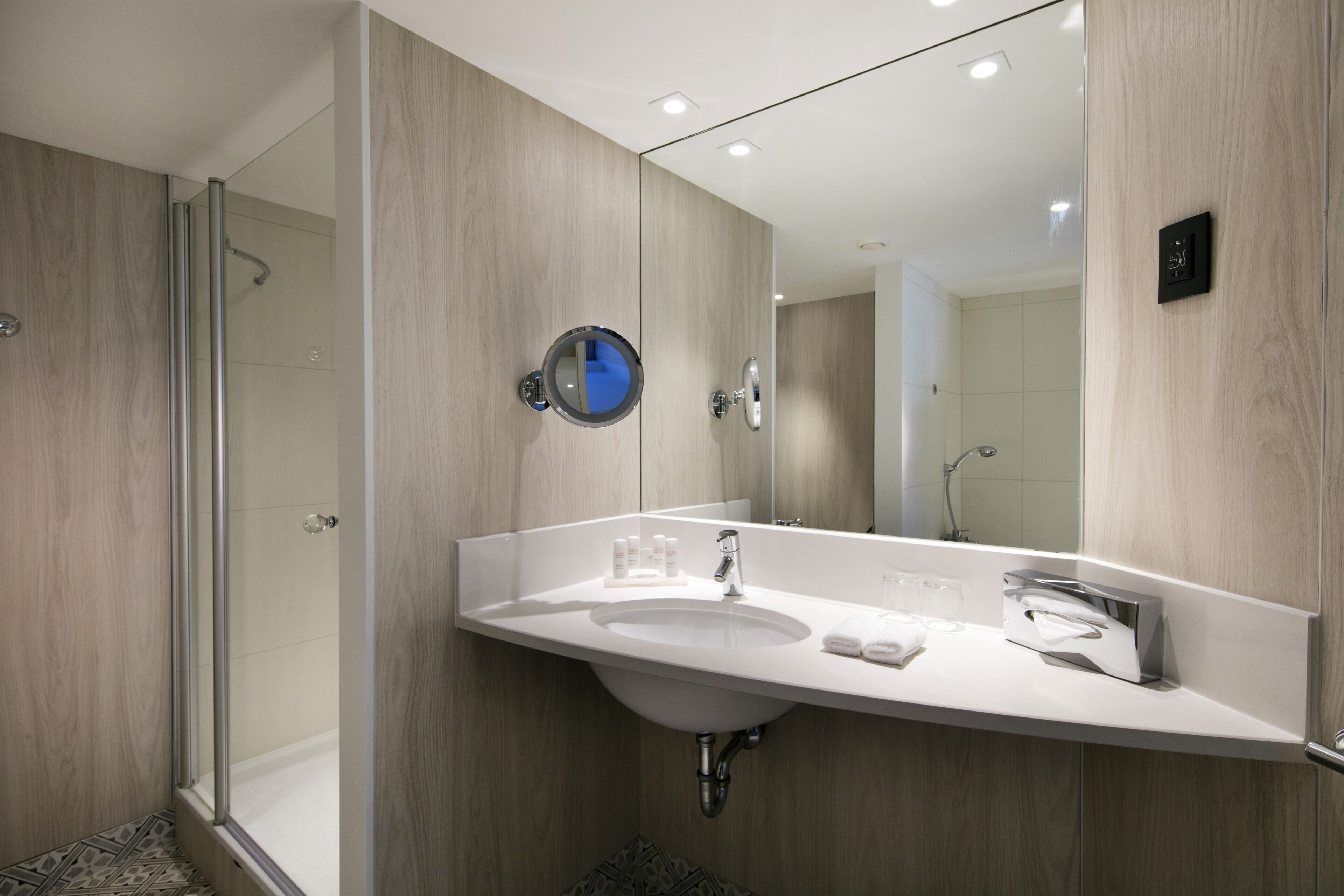 A modern bathroom with a wooden vanity, a sink, a mirror, and a shower area.