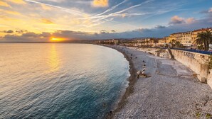Un paysage urbain côtier avec une plage de galets, une promenade et des bâtiments historiques.