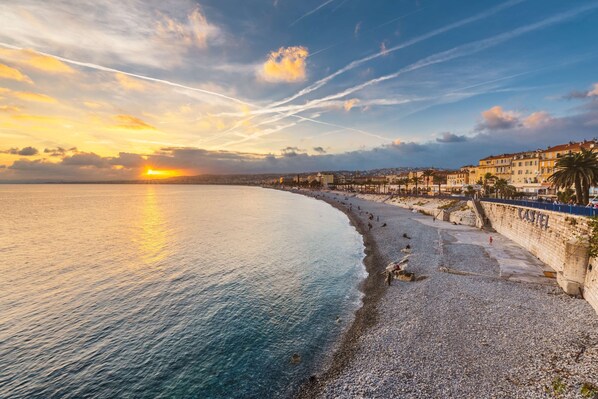 A coastal cityscape with a pebbled beach, a promenade, and historic buildings. - Radisson Blu Hotel, Nice (Nice)