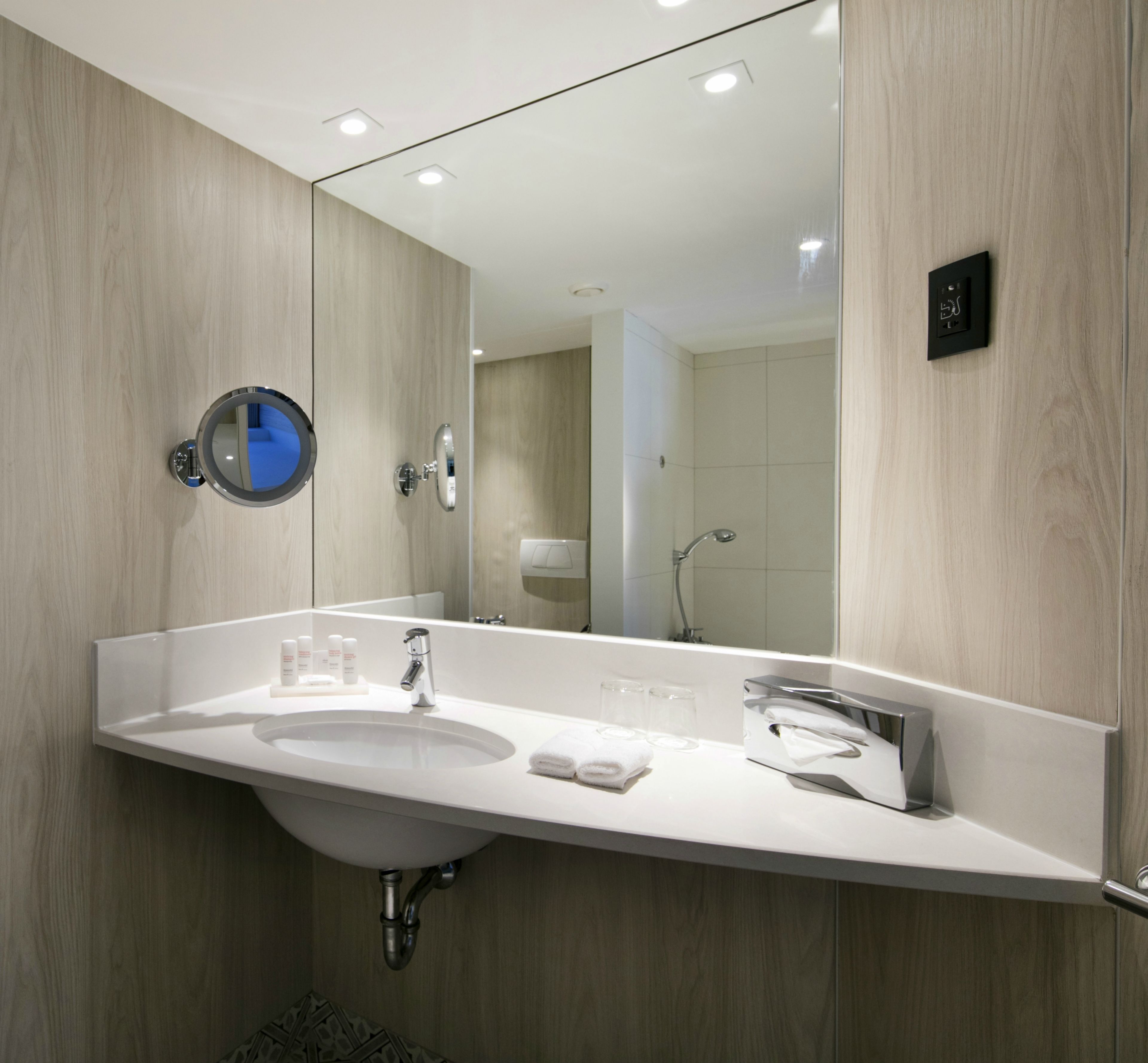 A modern bathroom with a large mirror, a sink, and a shower.