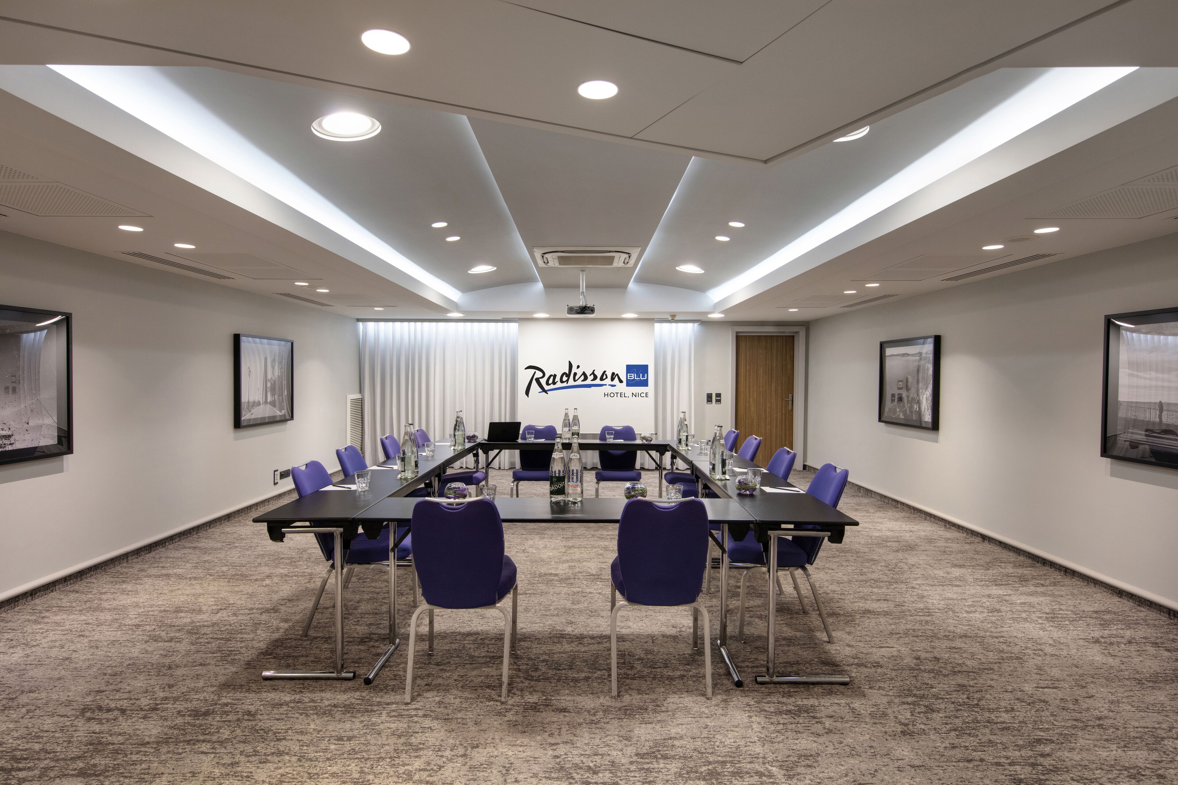 Ein Konferenzraum mit einem langen Tisch, violetten Stühlen und einem Schild des Radisson Blu Hotels.