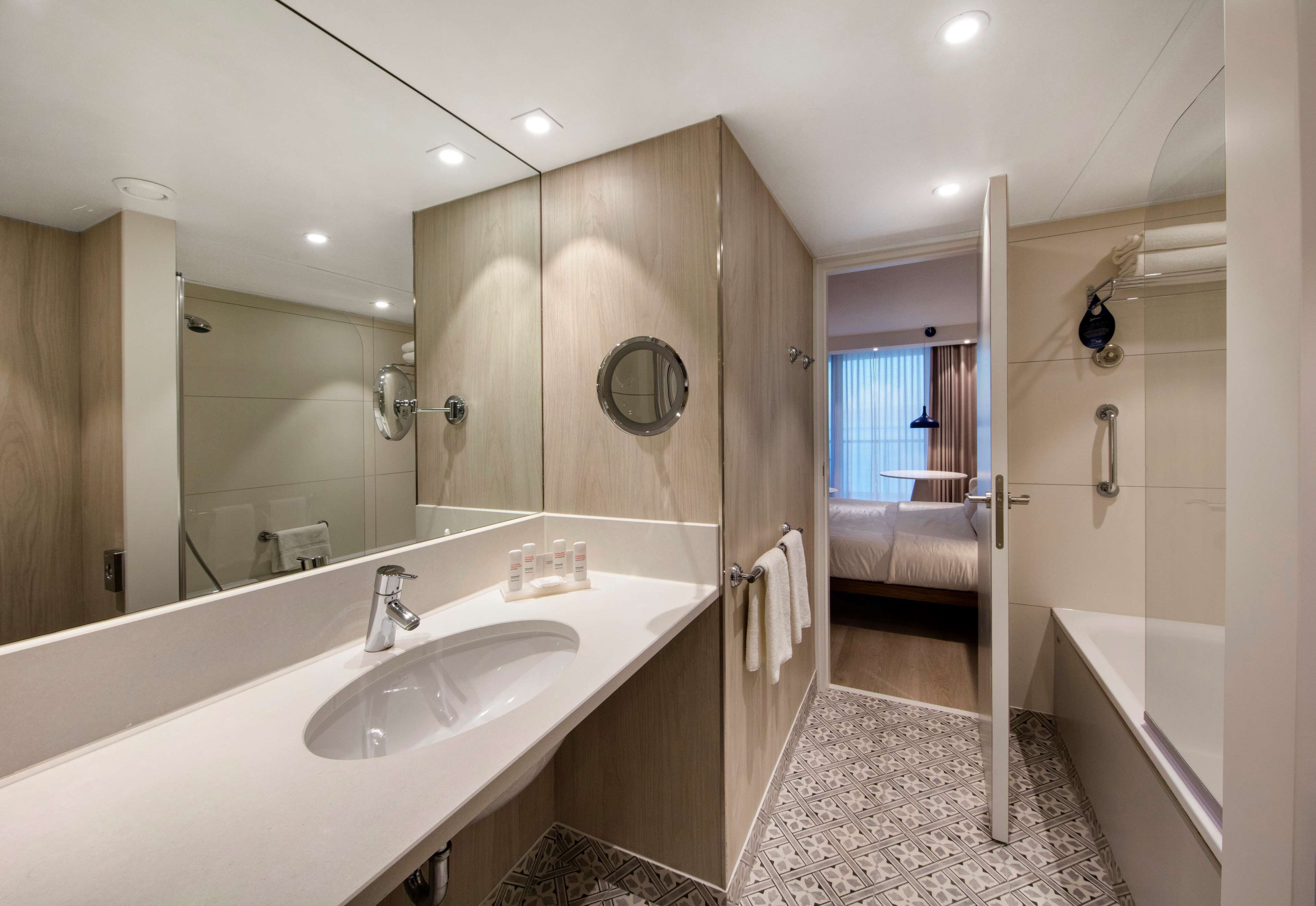 A modern bathroom with a large sink, mirror, and walk-in shower.