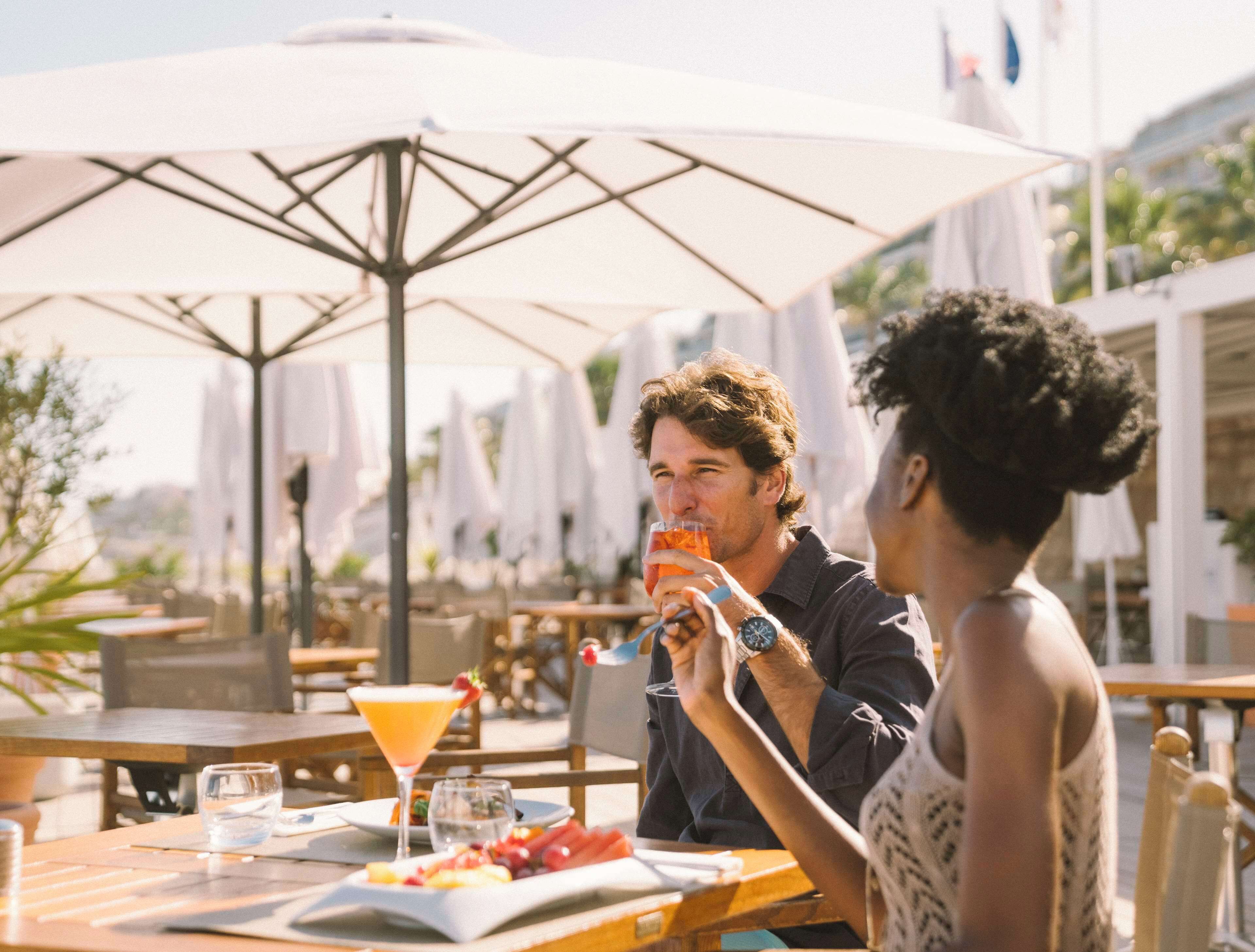 An outdoor dining area with tables, umbrellas, and a view of the cityscape.