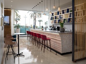 A modern bar area with a brick counter, red bar stools, and pendant lighting. - Radisson Blu Hotel, Nice (Nice)