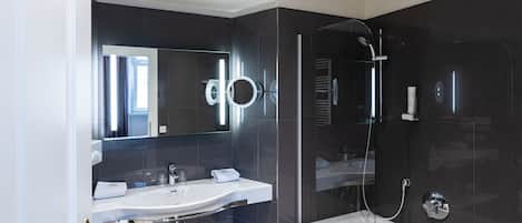 Un baño moderno con cabina de ducha de vidrio, un espejo grande y un lavabo blanco.