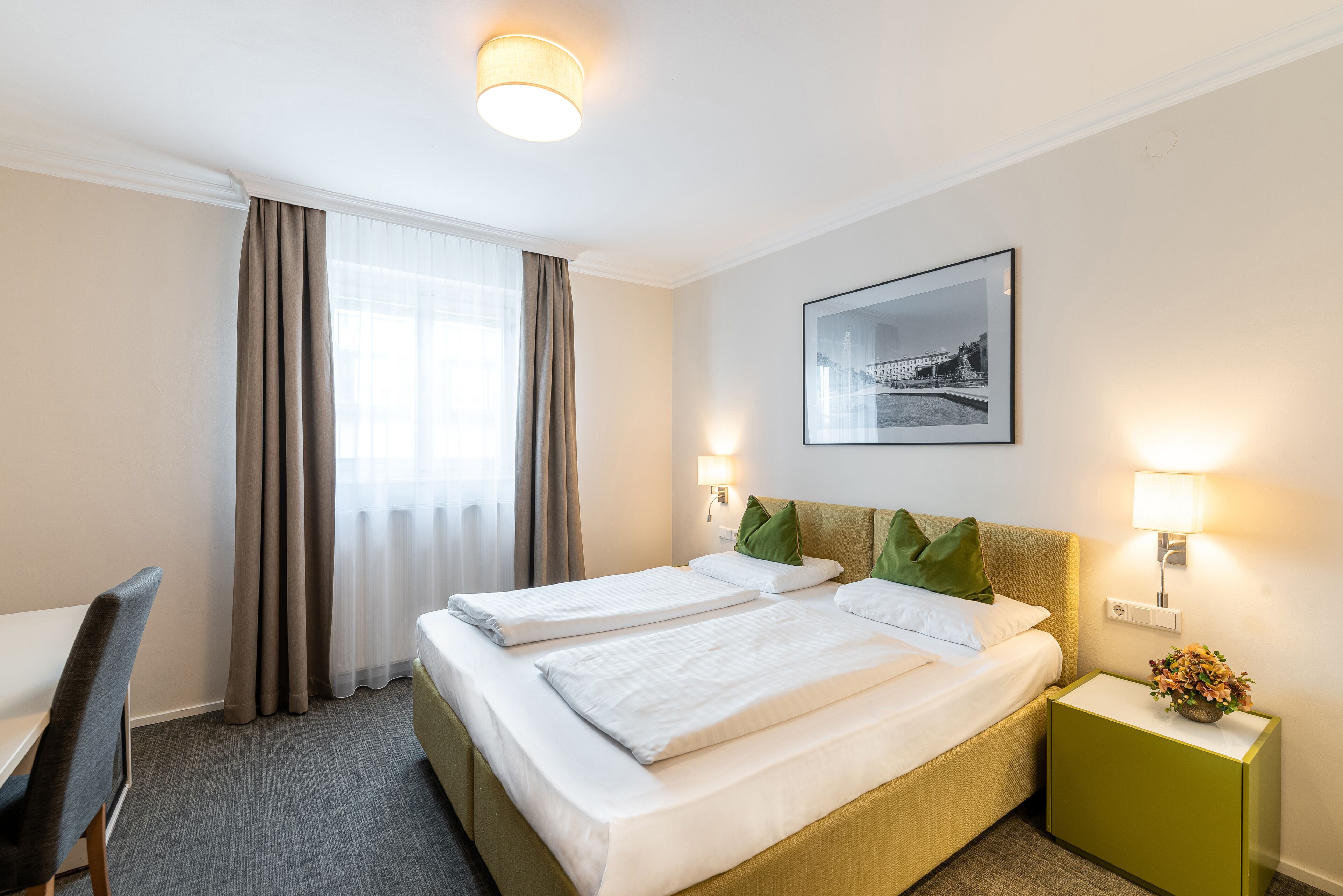 A hotel room with two beds, a desk, and a chair.