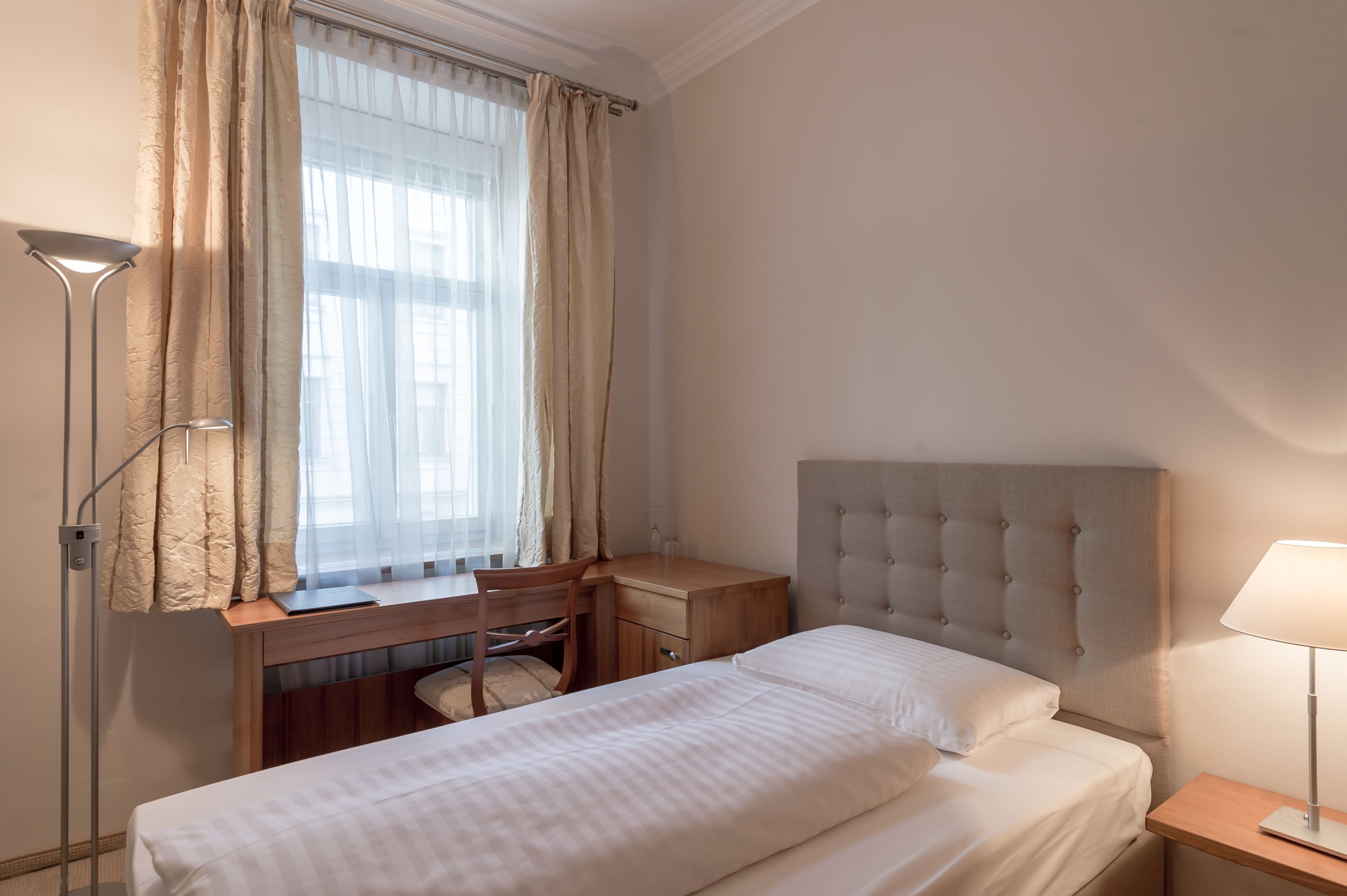 A bedroom with a bed, a desk, and a chair.