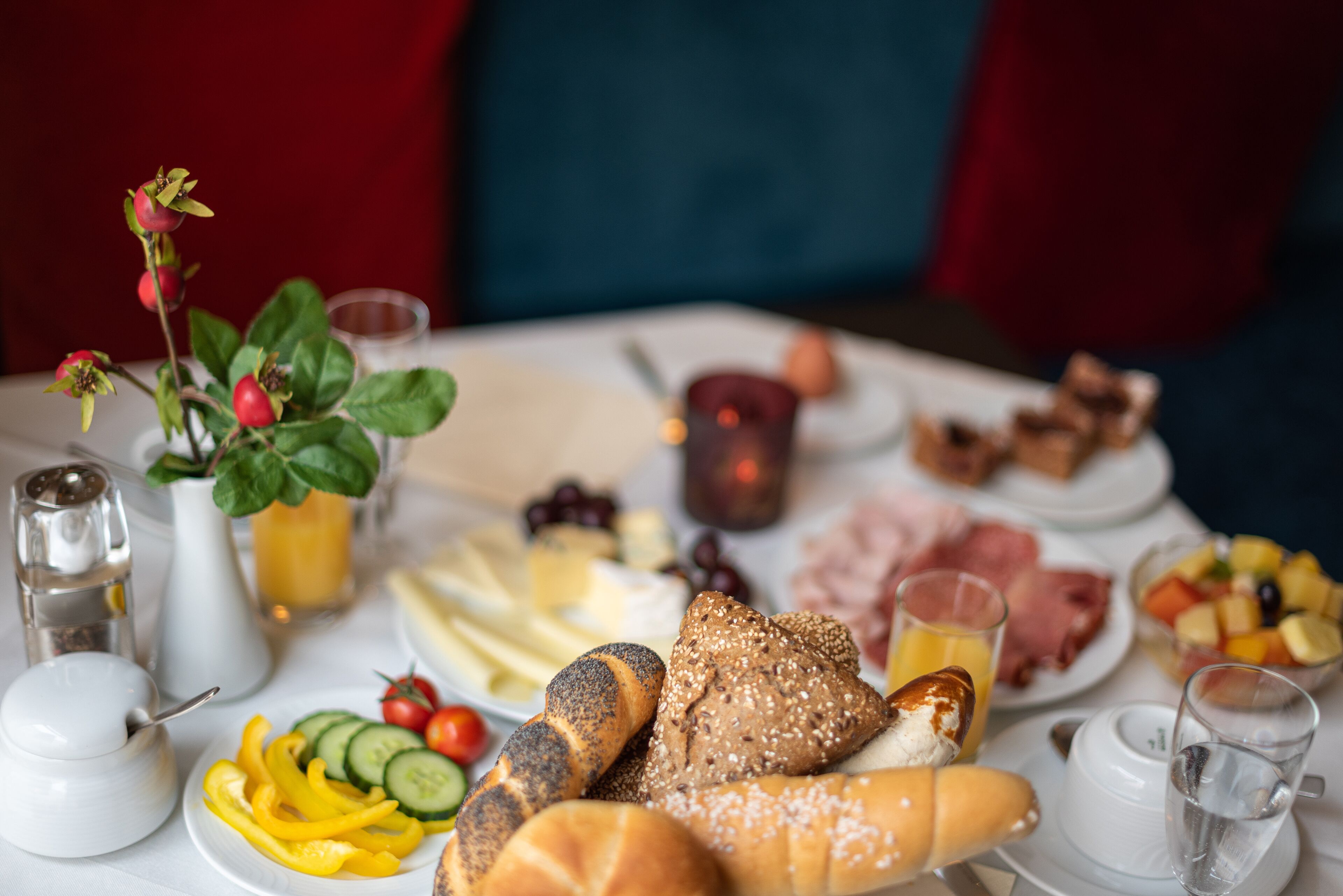A breakfast table with various food items, a salt and pepper shaker, a glass of orange juice, and a candle.