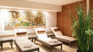 A spa area with four lounge chairs, a large wall mural, wooden slatted wall, and a tall green plant. - Altstadthotel Wolf-Dietrich (Salzburg)