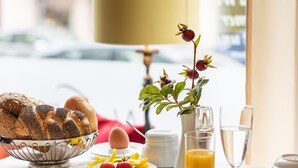A breakfast table with various food items, a vase with flowers, and a lamp. - Altstadthotel Wolf-Dietrich (Salzburg)