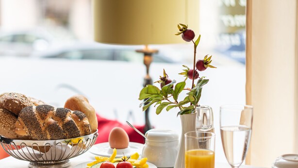 A breakfast table with various food items, a vase with flowers, and a lamp. - Altstadthotel Wolf-Dietrich (Salzburg)