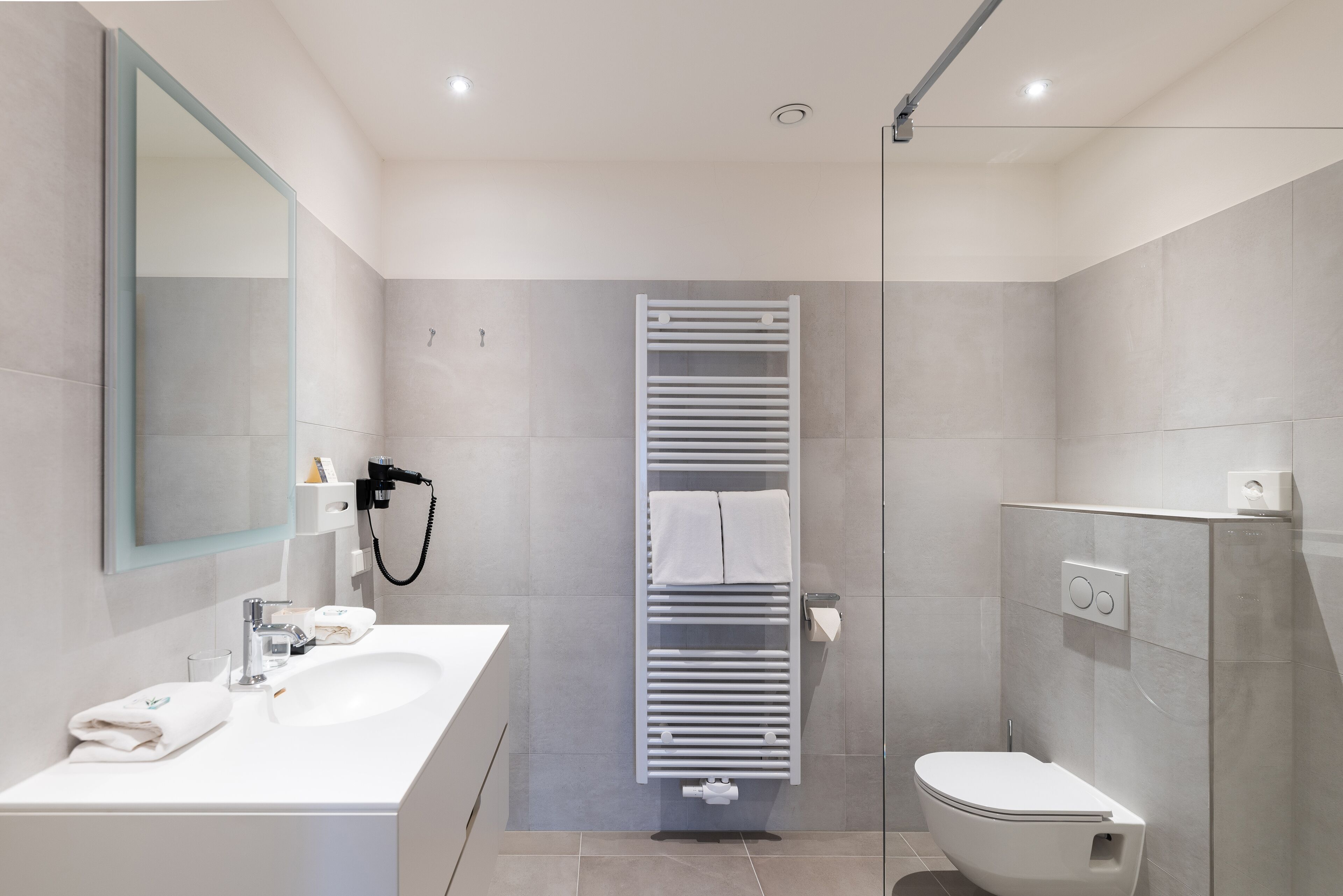 Ein modernes Badezimmer mit Waschbecken, Spiegel und Toilette in Weiß.