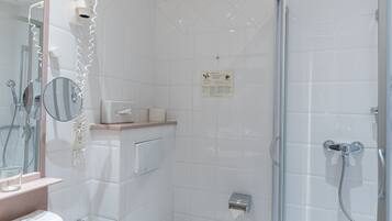 A modern bathroom with a glass-enclosed shower, a white toilet, and a sink with a mirror.