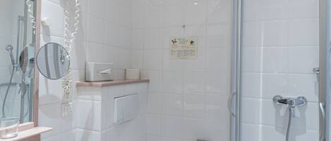 A modern bathroom with a glass-enclosed shower, a white toilet, and a sink with a mirror.