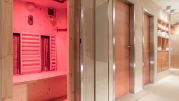 Ein moderner Hotelkorridor mit einem rot beleuchteten Raum links, einer Glastür rechts und einem Stauraum mit Regalen.