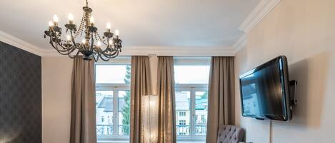 Habitación de hotel con cama, escritorio, televisión y vista a edificios a través de la ventana.