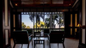 A room with a view of palm trees and a balcony. There are four chairs and a table in the center. - Hotel Cardoso (Maputo)