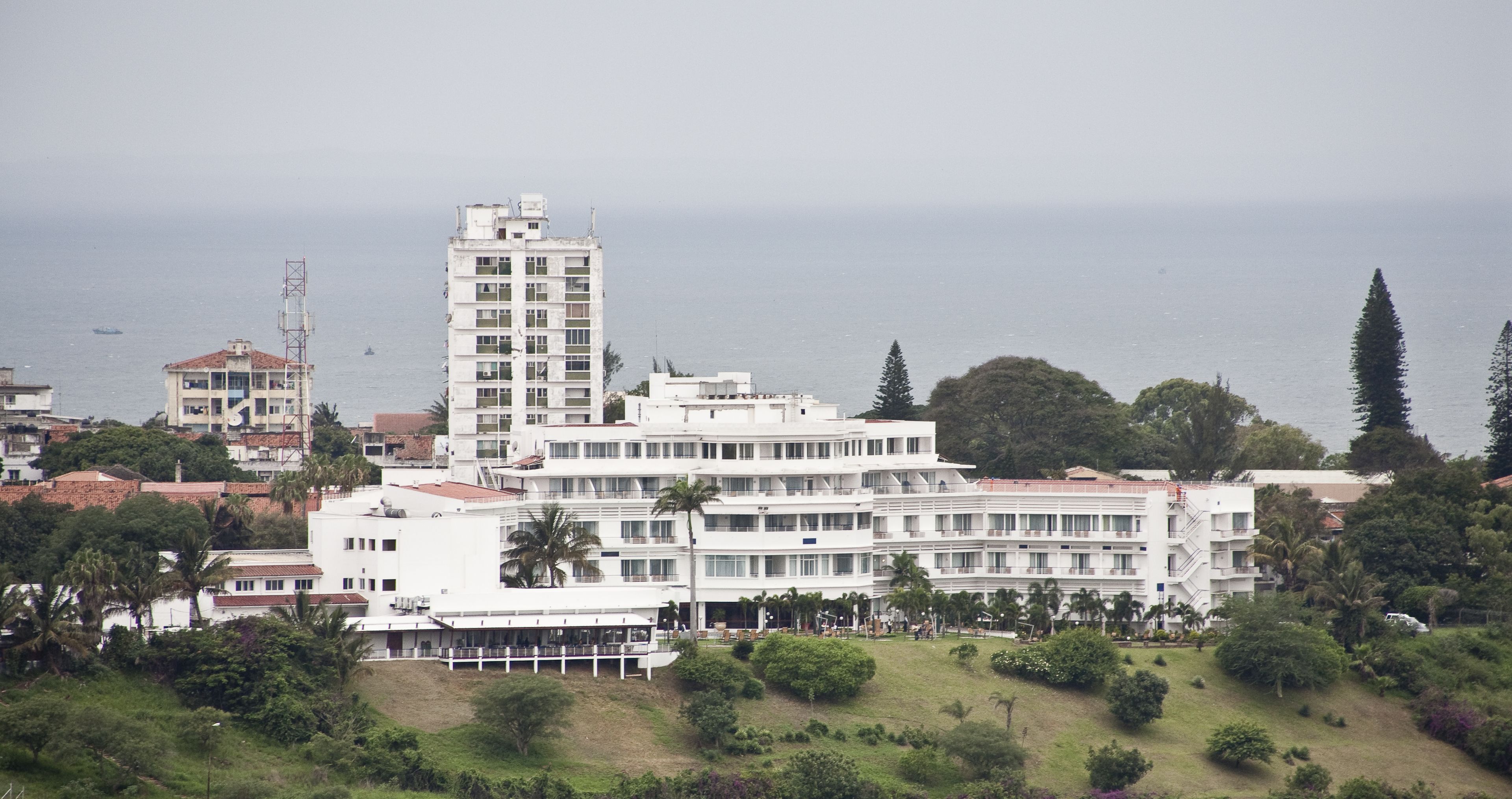 A multi-story hotel with balconies, situated near a body of water.