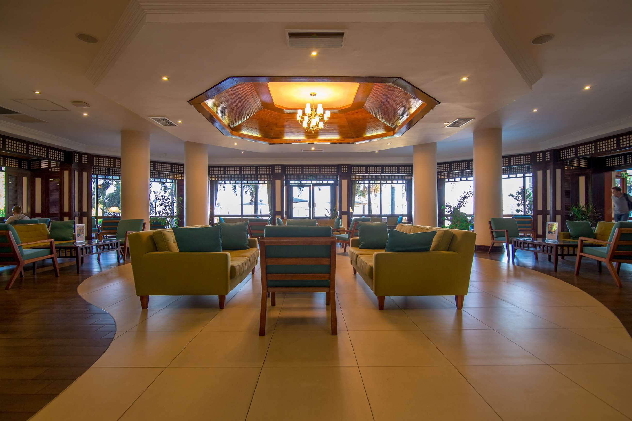 A spacious lobby with a central seating area, large windows, and a distinctive ceiling design.