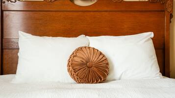 Ein Bett mit Holz-Kopfteil, zwei Kissen und einer weißen, strukturierten Tagesdecke.