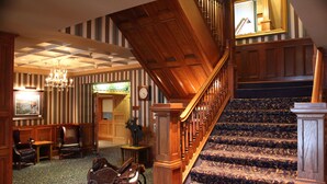 A grand staircase with ornate woodwork and patterned carpet, leading to a second floor.