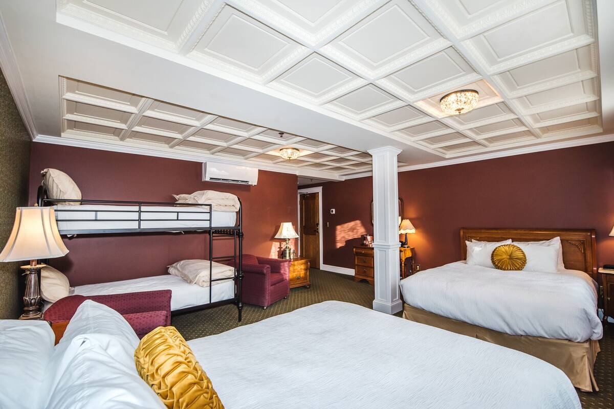 Una habitación de hotel con dos camas, una literas y un escritorio con una silla.
