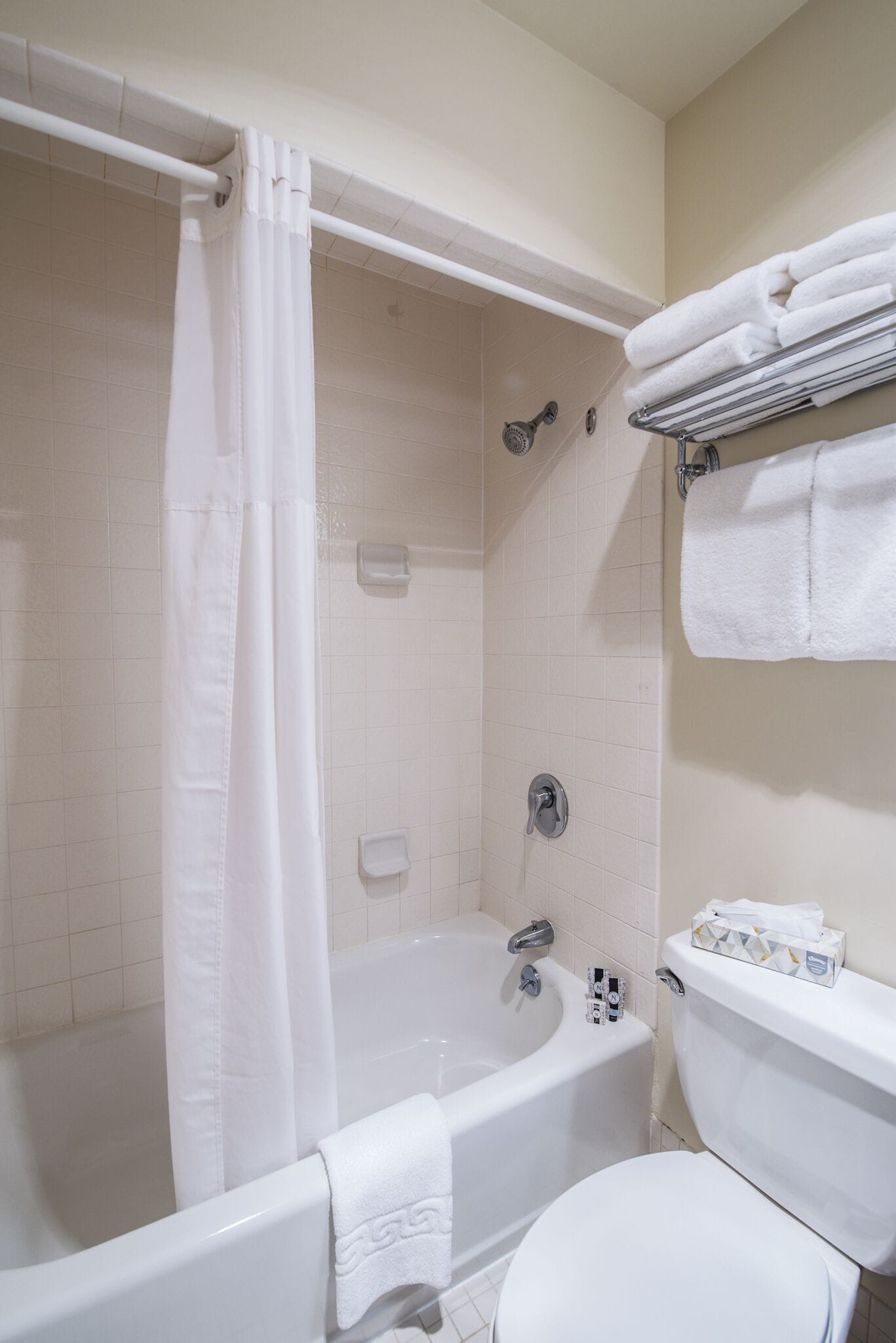 A bathroom with a bathtub, toilet, and a towel rack with folded towels.