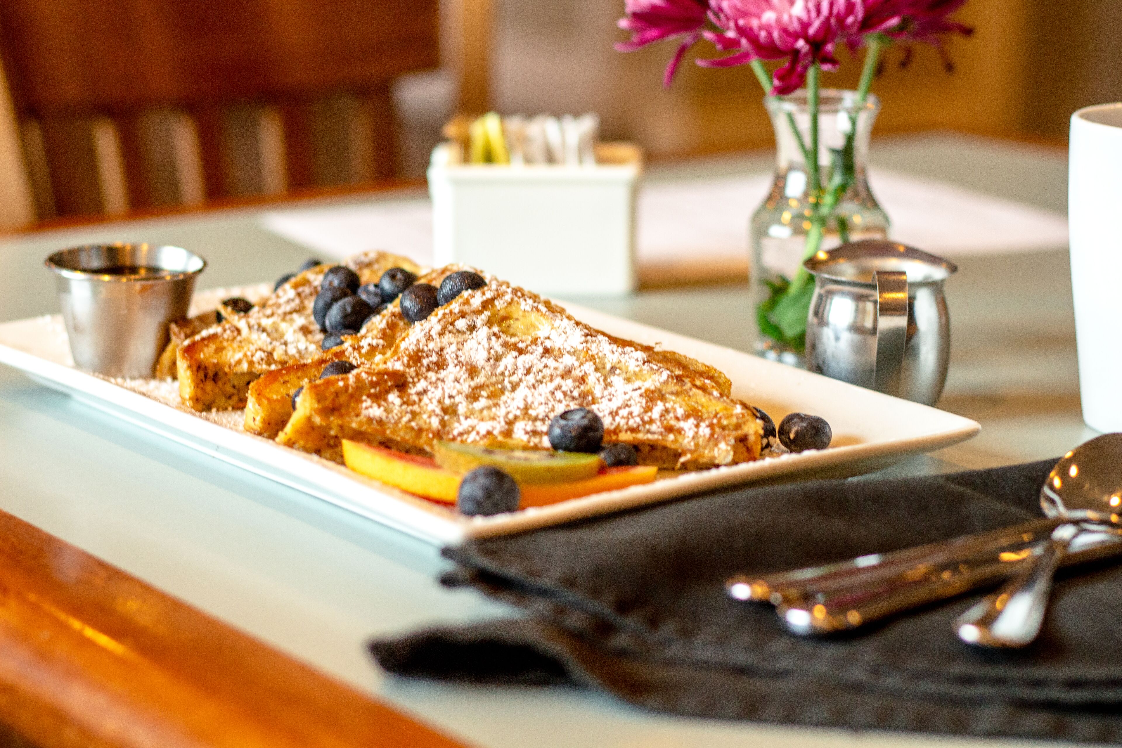 A breakfast plate with pancakes, blueberries, and powdered sugar.