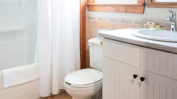 Et badeværelse med badekar, toilet og vaskebord med spejl.