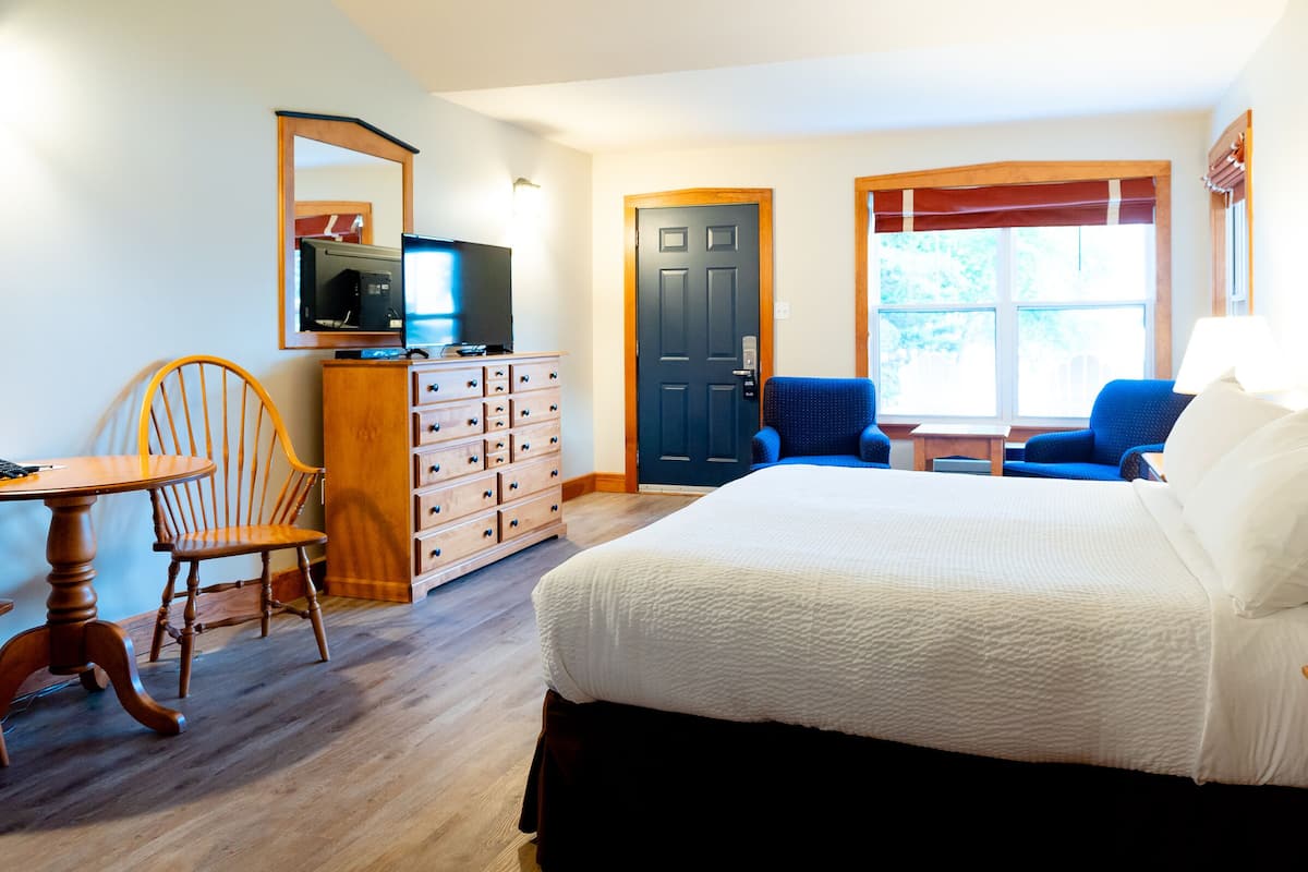 Un dormitorio con cama, cómoda, televisor, silla y escritorio.