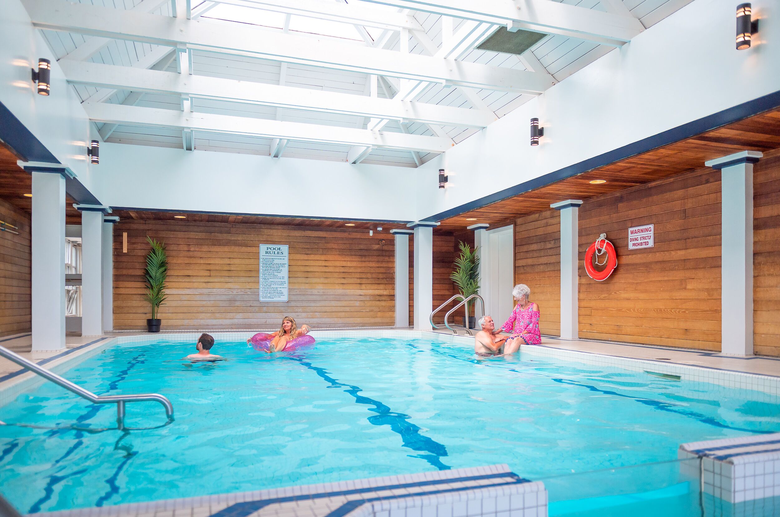 An indoor swimming pool with wooden walls and a high ceiling.