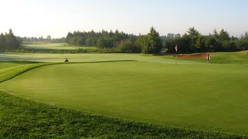 A golf course with a well-maintained green, sand bunkers, and a flagstick.