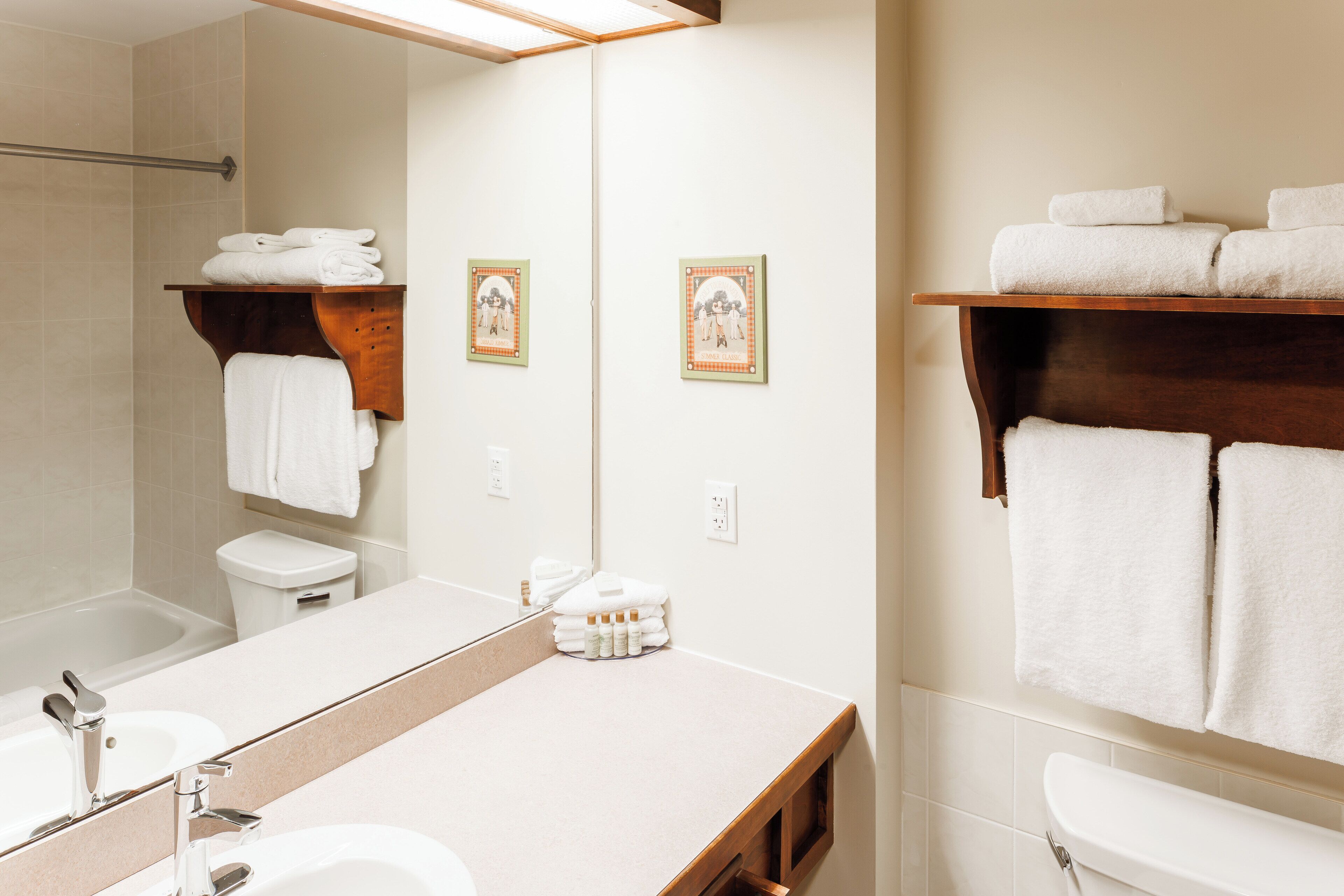 A modern bathroom with a large mirror, white sink, and two towel racks.