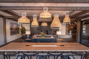 A spacious dining area with a long wooden table and modern chairs, surrounded by hanging wicker pendant lights. - Mill River Resort (Woodstock)