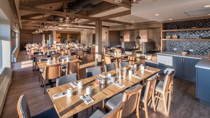 Un restaurante espacioso con mesas y sillas de madera, una zona de cocina y un diseño de interiores moderno.