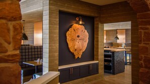 Interior de un restaurante con pared de madera, una placa de madera montada y una zona de bar.