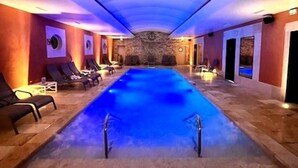 Un jacuzzi con pared de piedra, sillas de descanso y techo con lámpara.