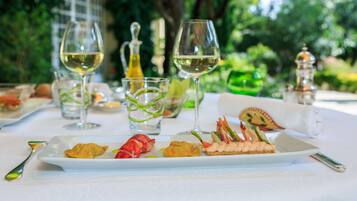 A dining table with a white tablecloth, plates of food, and two wine glasses.