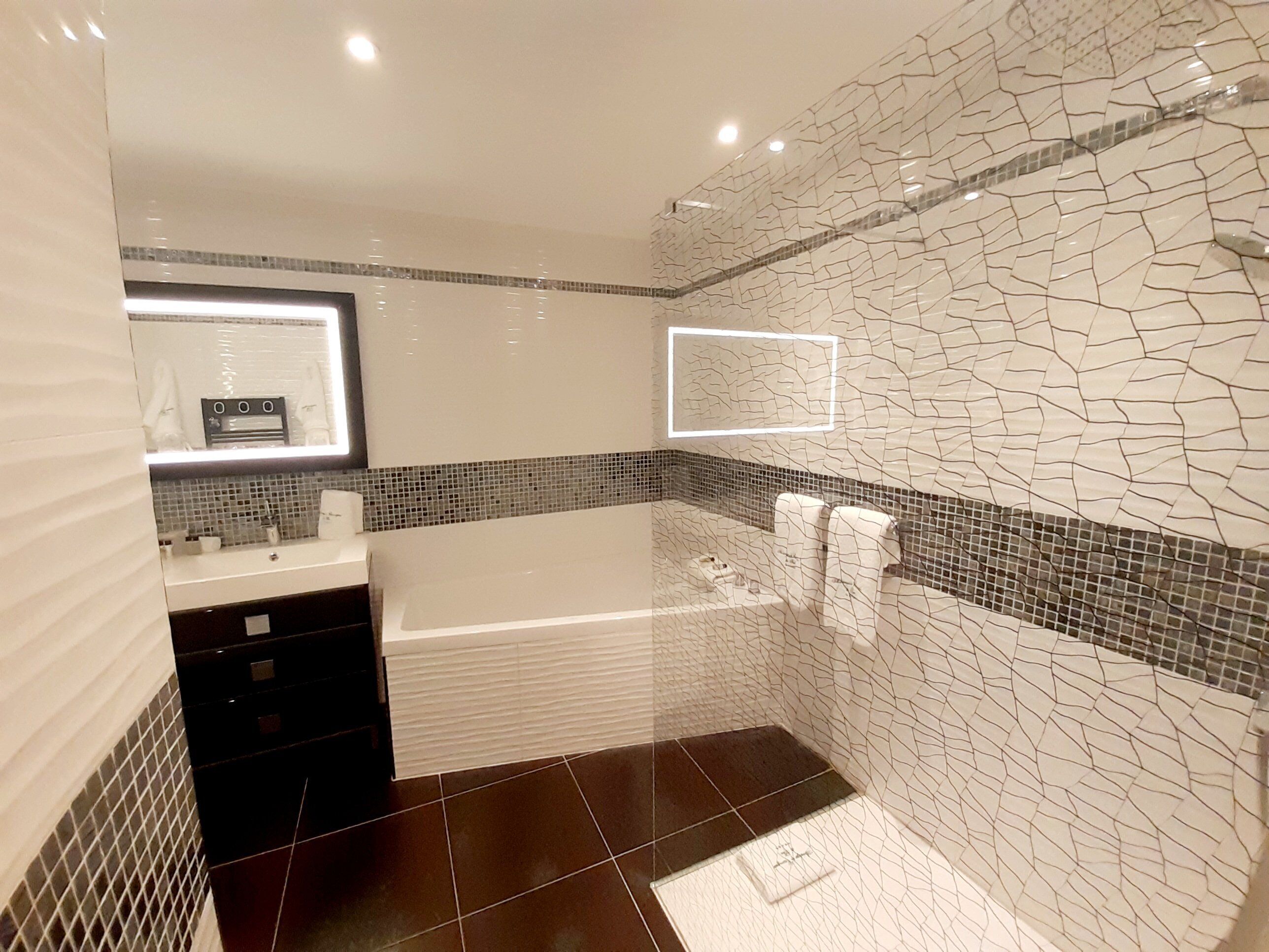 A modern bathroom with a bathtub, a vanity with a mirror, and a tiled shower area.