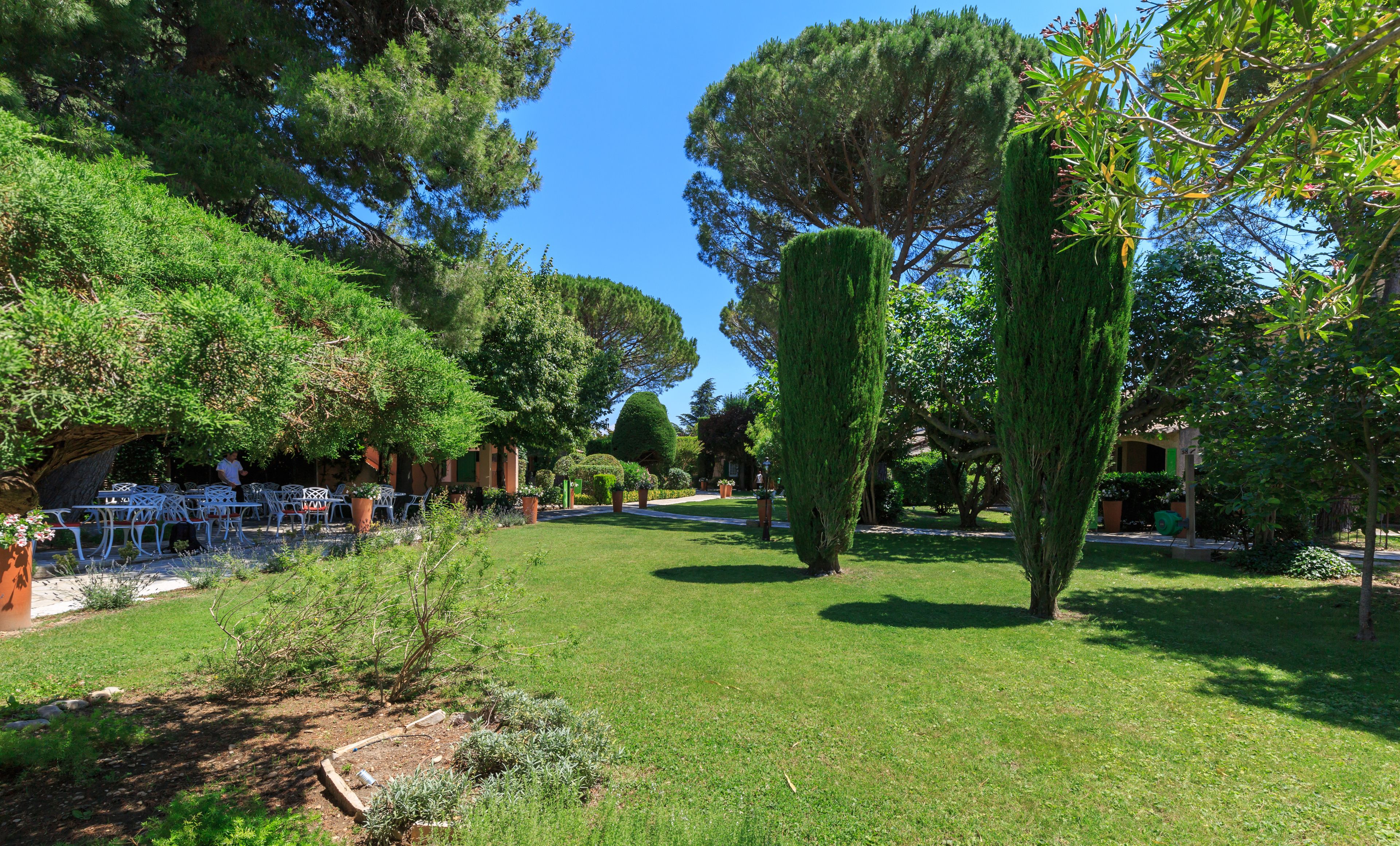 A well-maintained garden with neatly trimmed hedges, a variety of trees, and outdoor seating areas.