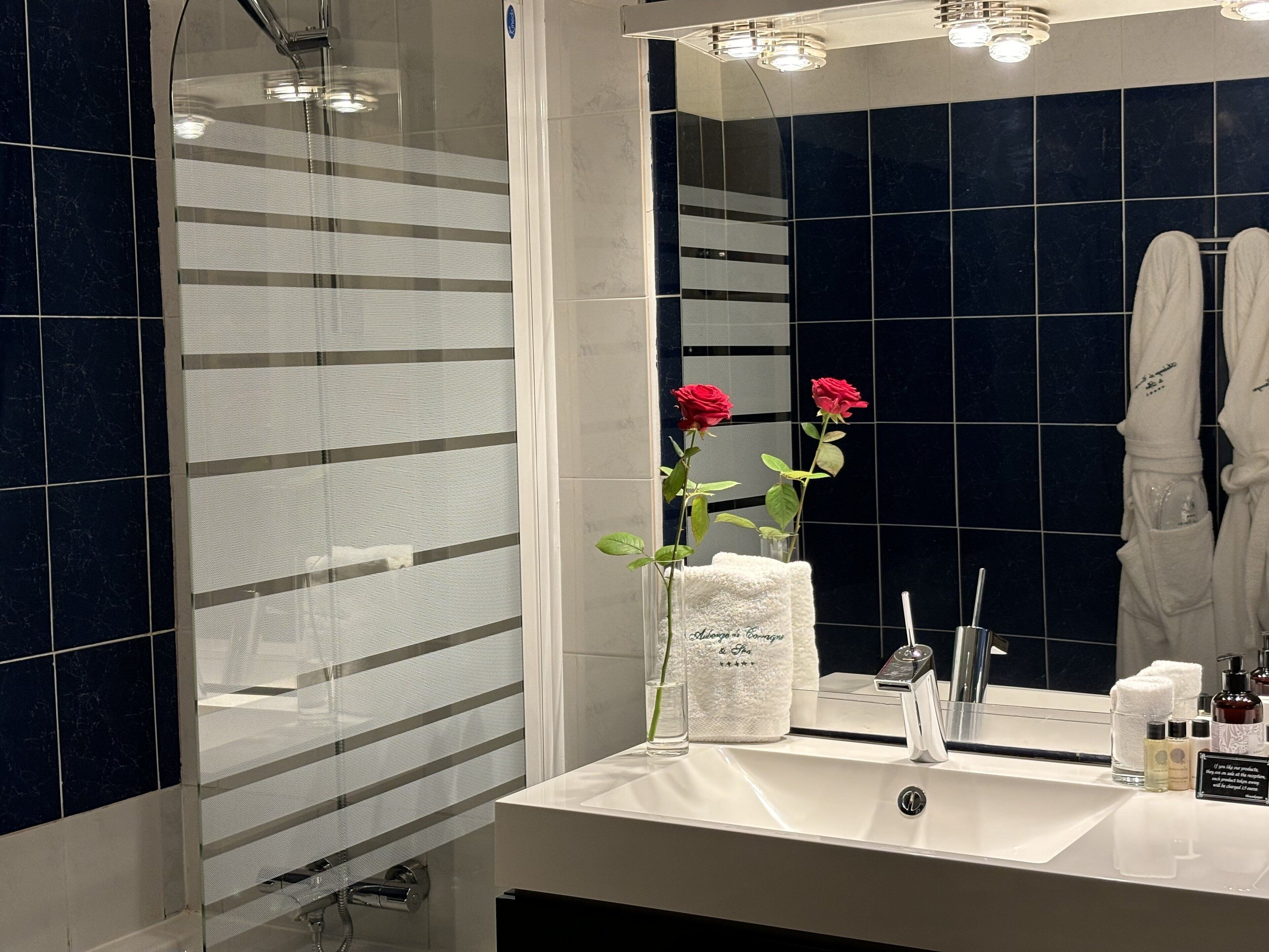 Une salle de bain moderne avec un grand miroir, un lavabo blanc et une cabine de douche en verre.